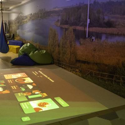 Interaktywna podłoga z projekcją gier w sali sensorycznej; pufy, huśtawka i wielkoformatowa fototapeta.
